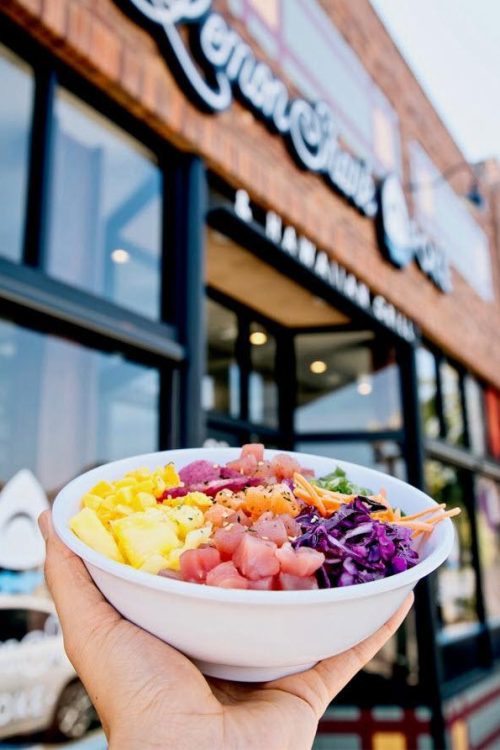 Poke bowl being held in front of store front